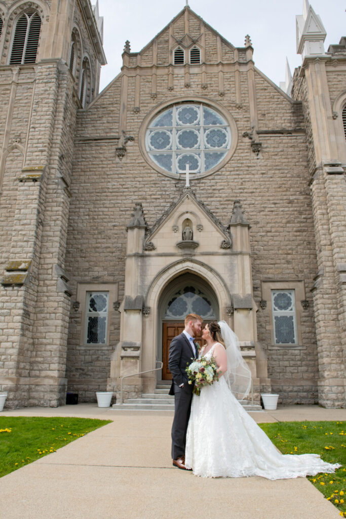 Bride and groom in front of a light brick church in MI