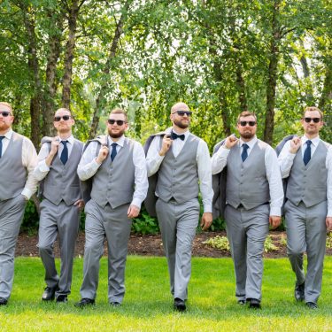 Groomsmen posing outside with jackets over one shoulder