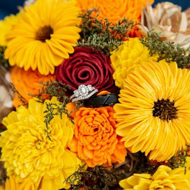 Wedding rings in yellow, red, and orange flowers