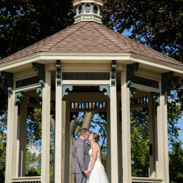 Bride and groom kissing in gazebo