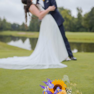 Bride and groom on golf course with flowers