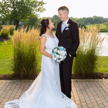 Bride and groom smiling in front of pond