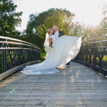Bride and groom kissing on wooden bridge