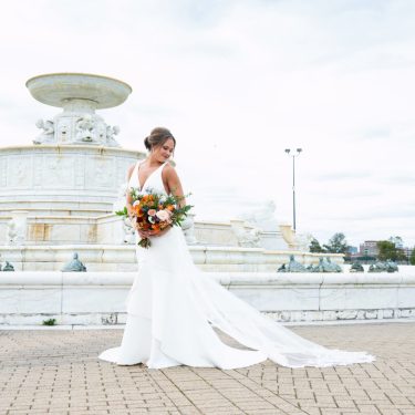 Bride in front of stone fountain in MI