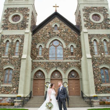 Bride and groom standing in front of stone church