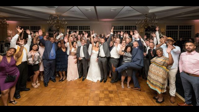People at a wedding reception with their hands up in the air.